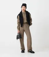 Pantalón de vestir de corte ancho, color marrón con textura tweed. Tiene cintura alta con trabillas, pliegues frontales, bolsillos laterales y un bolsillo trasero.
