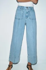 Jeans de tiro alto con corte wide leg cropped, confeccionados en denim de lavado claro. Presentan costuras marcadas en el frente, bolsillos de plastrón delanteros y cierre frontal con cremallera y botón.