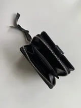 Billetera de cuero color plateado con cierre metálico, cuenta con múltiples compartimentos para tarjetas, billetes y monedas.