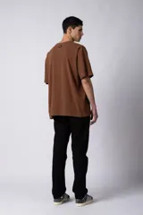 Remera de hombre color crudo, corte oversize, confeccionada en algodón grueso con textura micropanal. Diseño liso sin logos, con costura en forma de 'X' en la espalda. Ideal para un look casual y relajado.