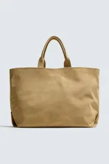 Bolso tipo shopper color beige confeccionado en piel con acabado serraje. Cuenta con doble asa de mano y compartimento principal con cierre magnético. El interior tiene un bolsillo con cierre de cremallera.