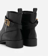 Bota de cuero negro con puntera redonda, caña corta con tirador, cierre lateral con cremallera y detalle de hebilla dorada con doble trabilla.
