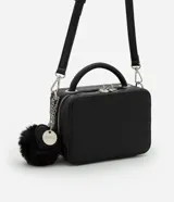 Cartera bandolera negra con textura en relieve, correa de mano, asa desmontable y pompón decorativo.