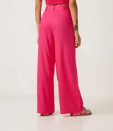 Conjunto de top y pantalón color fucsia. El top es corto, con tirantes finos y abertura en el centro. El pantalón es de corte palazzo, con cintura alta y bolsillos laterales.