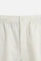 Pantalón relaxed fit de color beige con finas rayas verticales, confeccionado en una mezcla de algodón y cáñamo. Presenta cintura elástica, bolsillos laterales, un bolsillo trasero de plastrón y cierre frontal con botones.