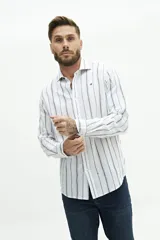 Camisa de manga larga para hombre, color blanco con rayas verticales finas en tonos grises y azules. Confeccionada en una mezcla de lino y algodón, de corte semi slim y logo bordado en el pecho.