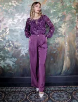 Pantalón palazzo de tiro alto color violeta, de satén. Tiene pretina delantera con pasadores, botón y cierre, pretina trasera elastizada y bolsillos verticales delanteros.