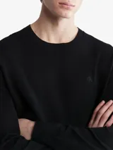 Sweater negro de algodón con cuello redondo, mangas largas con puños acanalados y logo de la marca bordado en el pecho.