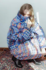 Campera puffer con estampado a cuadros en tonos azul, rojo, amarillo y blanco. Diseño capitoneado a mano y forro interior verde. Corte holgado. Ideal para usar con un look casual.