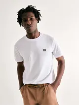 Camiseta blanca de algodón con cuello redondo y mangas cortas. Estampa rectangular con borde negro que contiene la frase "NATURAL ATMOSPHERE" en letras mayúsculas y una imagen de montañas y mar.