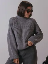 Sweater color crema de tejido de punto con cuello alto y diseño geométrico en la parte superior.