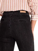 Pantalón de jean negro con corte boot leg, tiro alto y cierre frontal con botones dorados.