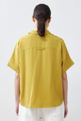 Camisa color pistacho de lyocell con cuello clásico, cierre frontal con botones y mangas cortas.