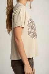 Remera color arena de algodón peinado con estampa frontal de texto con diseño floral.