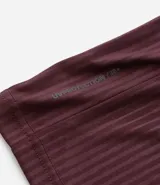 Remera deportiva de manga corta y cuello redondo, color beige claro, con textura acanalada vertical. Presenta detalles reflectantes en los hombros.