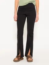Pantalón negro de punto tramado con cintura elastizada, corte al cuerpo y tajos en el ruedo.