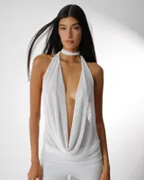 Vestido blanco de microtul premium, con escote halter profundo y drapeado en el busto. La prenda es ajustada en la parte superior y presenta un pantalón ancho y transparente debajo.