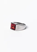 Anillo plateado de acero quirúrgico con piedra roja cuadrada en el centro.
