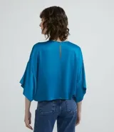 Blusa celeste de viscosa con textura satinada, cuello redondo, manga corta con sisa desplazada y abertura en la espalda.