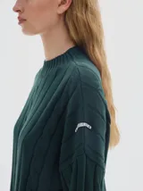 Buzo tejido color blanco, con cuello subido tipo polera, diseño oversized y largo con pequeños cortes laterales.