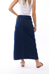 Falda midi de jean azul oscuro, con corte recto, abertura frontal y cierre con botones metálicos.