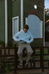 Buzo con capucha celeste, de manga larga y fit loose. Confeccionado en tejido loop back cepillado por dentro, con mangas ranglán, puños de canalé, forro de la misma tela en el interior de la capucha y estampa en goma de tacto suave ubicada en la espalda.