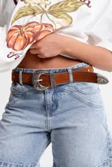 Cinto de cuero color marrón con hebilla, pasador y puntera metálicos con diseño floral.