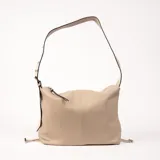 Bolso tipo hobo color beige con textura granulada y correa de hombro ajustable. Cierre superior con cremallera y tiras decorativas laterales con detalle de nudo.