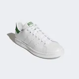 Championes Adidas Stan Smith, modelo clásico de corte bajo, color blanco con detalles en verde. Presentan una parte superior de cuero sintético, perforaciones laterales en lugar de las tres franjas y talón en color verde con logo.