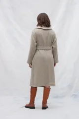 Tapado largo color beige con diseño de espiga, cuello solapa, cierre cruzado con cinturón y bolsillos laterales. Confeccionado en lana fina sin teñir.