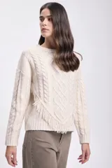 Sweater color crudo de tejido de punto con diseño de trenzas y flecos en el frente.