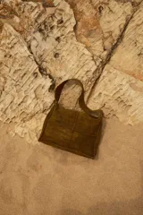 Bolso de hombro marrón de cuero con diseño de paneles rectangulares cosidos.