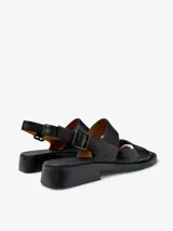 Sandalias de cuero vacuno color negro, con dos tiras anchas sobre el empeine, tira trasera con hebilla ajustable y suela baja con pequeño taco cuadrado.
