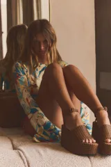 Sandalias con plataforma tipo cuña color marrón, con cuerpo trenzado, tira delantera y cierre mediante tira con hebilla a la pulsera del tobillo.
