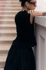 Top negro sin mangas de viscosa con diseño smock, escote barco con volados y peplum.
