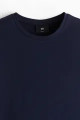Remera azul marino de punto liviano de mezcla de algodón, de manga larga con cuello redondo ribeteado y bajo recto. Corte ajustado que realza el contorno del cuerpo creando una silueta entallada.