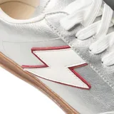 Zapatillas plateadas de cuero sintético con suela marrón, cordones blancos, talón azul y detalle de rayo blanco con borde rojo en el lateral.