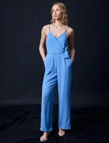 Enterito celeste de crepe marca Luxology, con escote en V cruzado, cintura elastizada, espalda en punto smock y tirantes con detalle de cadenas.