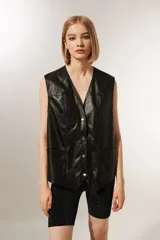 Chaleco negro de cuero sintético con cuello en V, sin mangas y corte holgado.