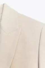 Blazer negra de corte clásico, con cuello solapa, manga larga, bolsillos frontales con solapa y cierre frontal con un botón.