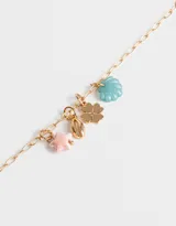 Set de dos pulseras elásticas: una de hilo con cuentas de colores pastel y otra dorada con dijes colgantes de estrella de mar rosa, caracol dorado, trébol dorado y concha azul.