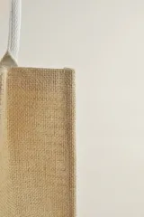 Bolso tipo tote de yute con rayas horizontales color beige y manijas de soga blanca.