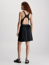 Vestido corto negro de Calvin Klein Jeans con corte evasé, breteles anchos y espalda deportiva. Presenta una banda elástica con el logo de la marca en la cintura.