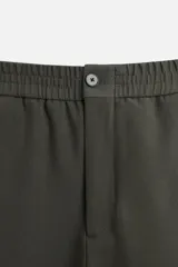 Pantalón largo color verde oscuro, de corte recto y tiro medio. Confeccionado en tejido con viscosa, con cintura elástica, bolsillos laterales y trasero de vivo. Cierre frontal con cremallera y botón.