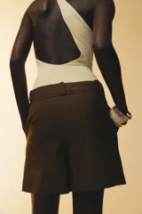 Shorts color marrón confeccionados en hilatura con algodón. Tiro alto y cintura doble con trabillas, bolsillos laterales y falso bolsillo con solapa en delantero. Detalle de costuras a contraste y cierre frontal con cremallera y ganchos metálicos.