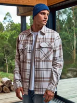 Sobrecamisa a cuadros color crema, marrón y blanco, de manga larga con cierre de botones y bolsillos en el pecho.