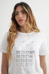 Remera blanca de algodón con cuello redondo y estampado frontal con la frase "Ready to Start" repetida en color plateado.