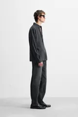 Camisa negra relaxed fit confeccionada en tejido fluido con mezcla de viscosa. Tiene cuello solapa, manga larga con puño abotonado y cierre frontal con botones.