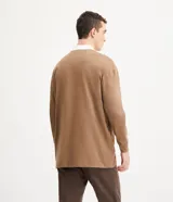 Remera polo de hombre color marrón, corte relaxed, confeccionada en media malla de algodón. Presenta cuello camisero blanco contrastante, tapeta con botones, mangas largas con sisa desplazada y puños ajustados.