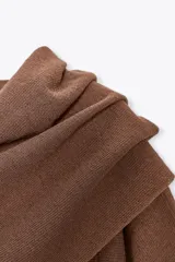 Top color crema de tejido de punto, con cuello asimétrico y mangas anchas.